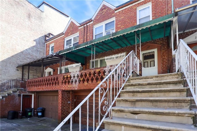 view of exterior entry featuring a garage, brick siding, and driveway