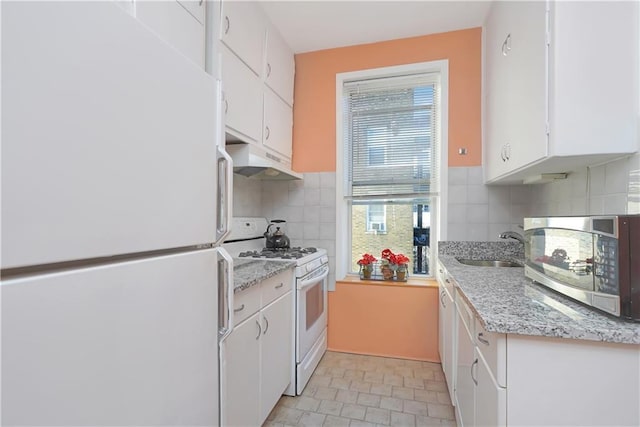 kitchen featuring white appliances, backsplash, white cabinetry, and sink