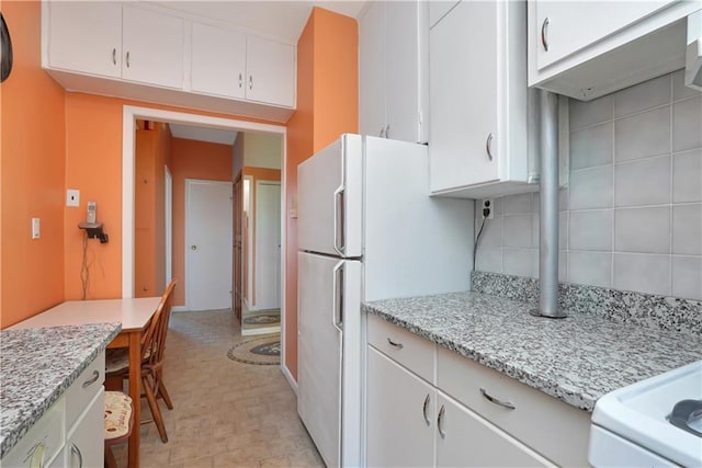 kitchen featuring light stone countertops, white cabinets, and white fridge