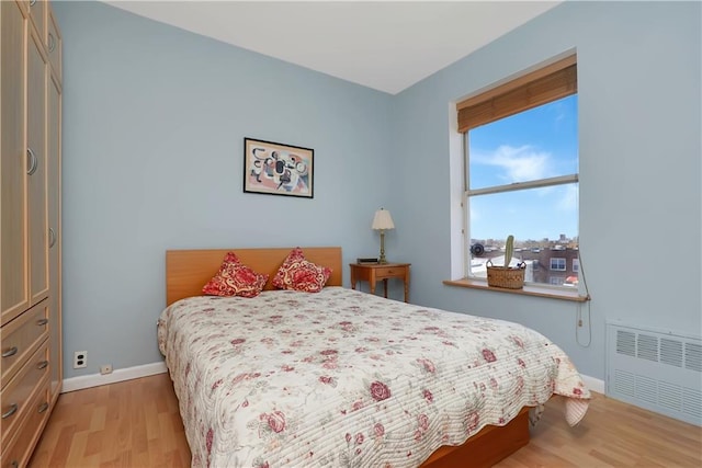 bedroom with radiator heating unit and light hardwood / wood-style flooring