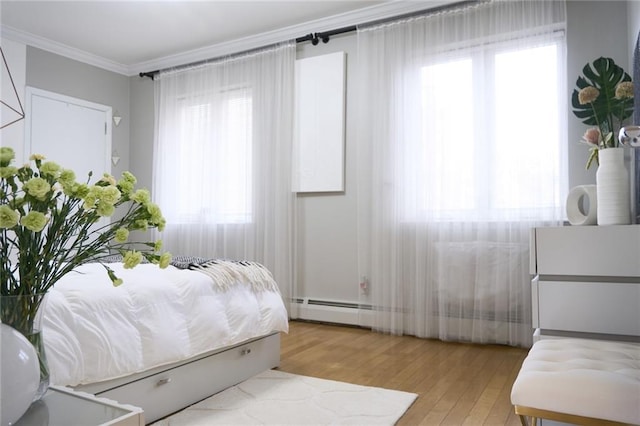 bedroom with light hardwood / wood-style floors, multiple windows, ornamental molding, and a baseboard heating unit