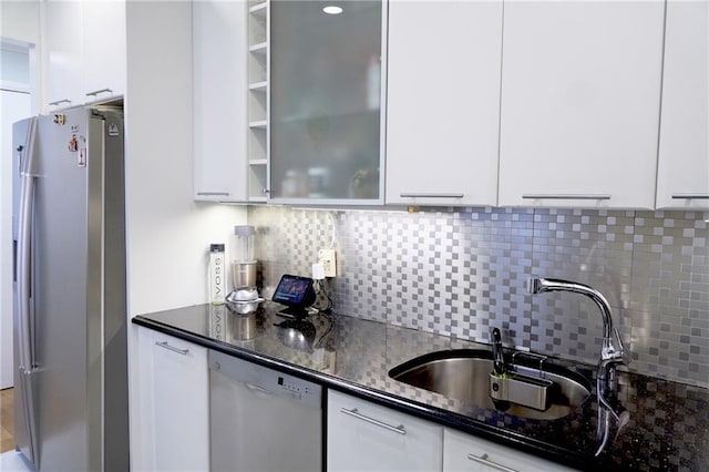 kitchen with tasteful backsplash, appliances with stainless steel finishes, sink, dark stone counters, and white cabinets