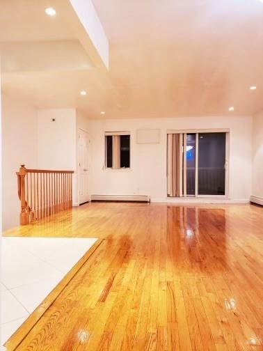 empty room with a baseboard heating unit and hardwood / wood-style flooring