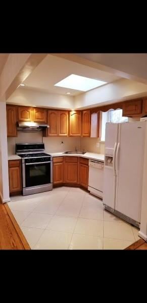 kitchen featuring light tile patterned floors, sink, a raised ceiling, and white appliances