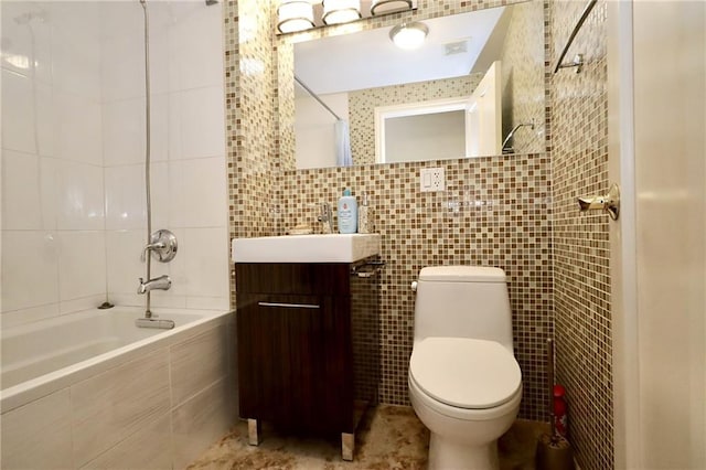 full bathroom with tiled shower / bath combo, toilet, tile walls, and vanity