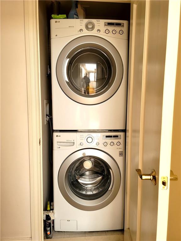 clothes washing area with light tile patterned floors and stacked washer / drying machine