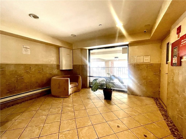 interior space featuring light tile patterned flooring, tile walls, and a baseboard radiator