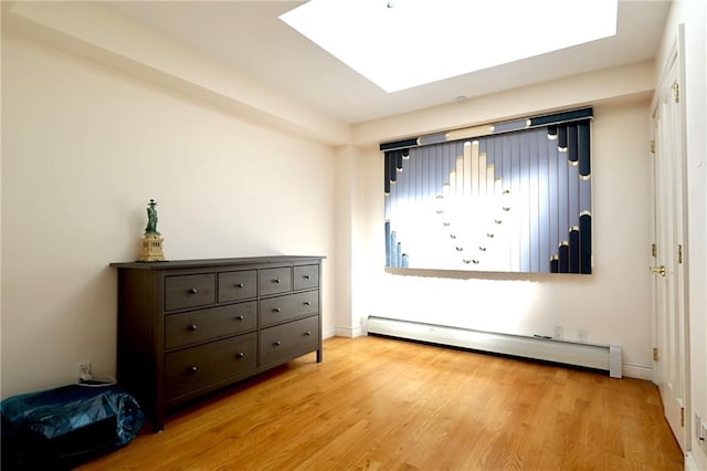 unfurnished bedroom featuring a baseboard radiator, a skylight, and light hardwood / wood-style floors