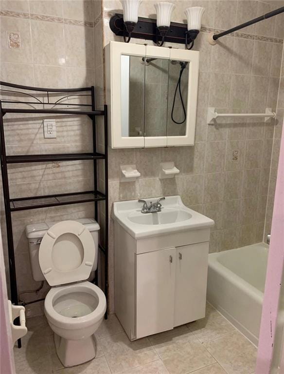 full bathroom with tile patterned floors, toilet, tiled shower / bath, tile walls, and vanity