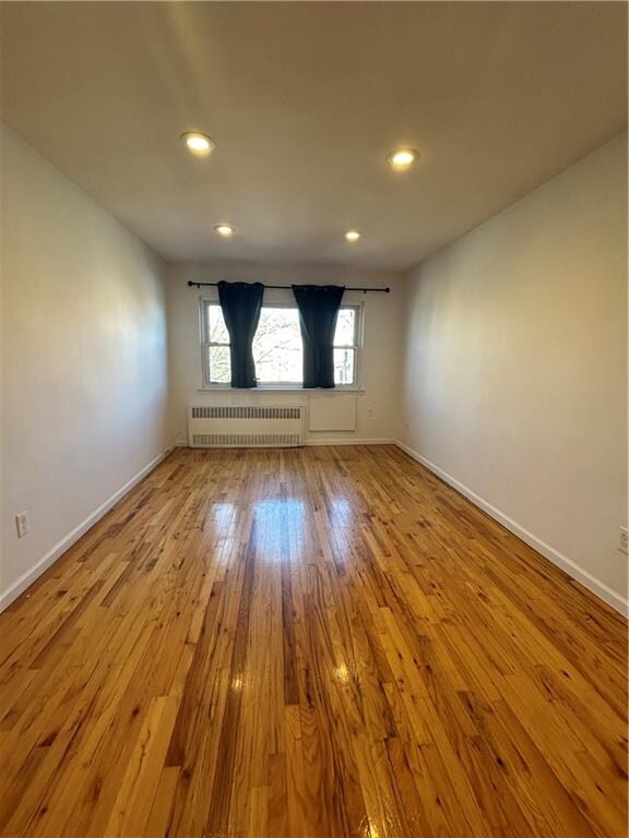 unfurnished room with radiator heating unit and light hardwood / wood-style floors