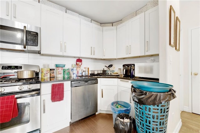 kitchen with white cabinets, appliances with stainless steel finishes, and tasteful backsplash