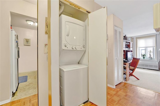 clothes washing area with stacked washer / dryer, laundry area, and light colored carpet