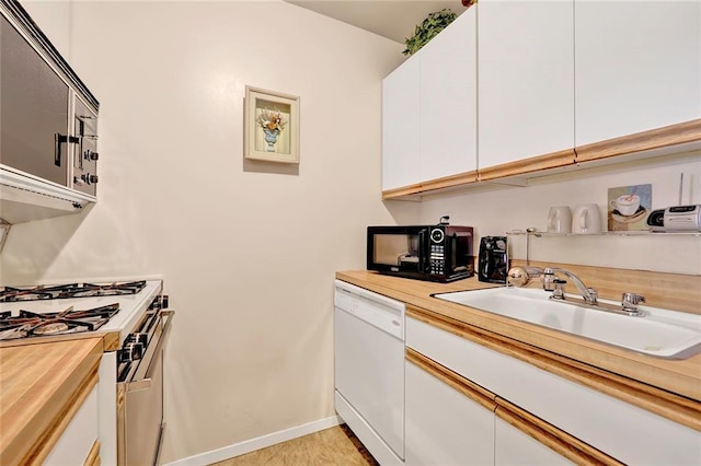 kitchen featuring white cabinetry, a sink, wood counters, white appliances, and baseboards