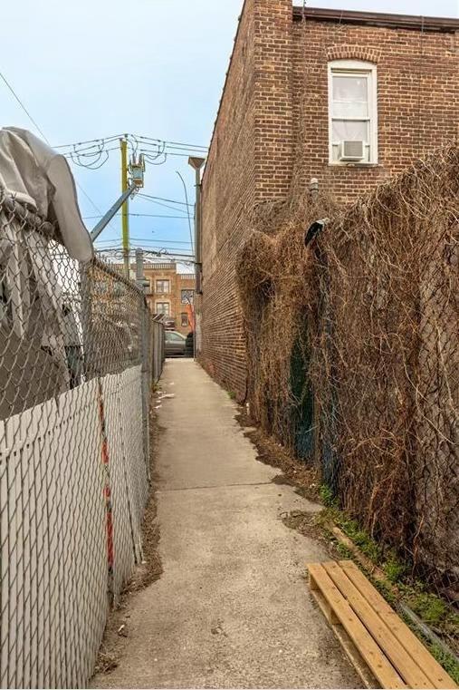 view of side of property featuring brick siding and fence