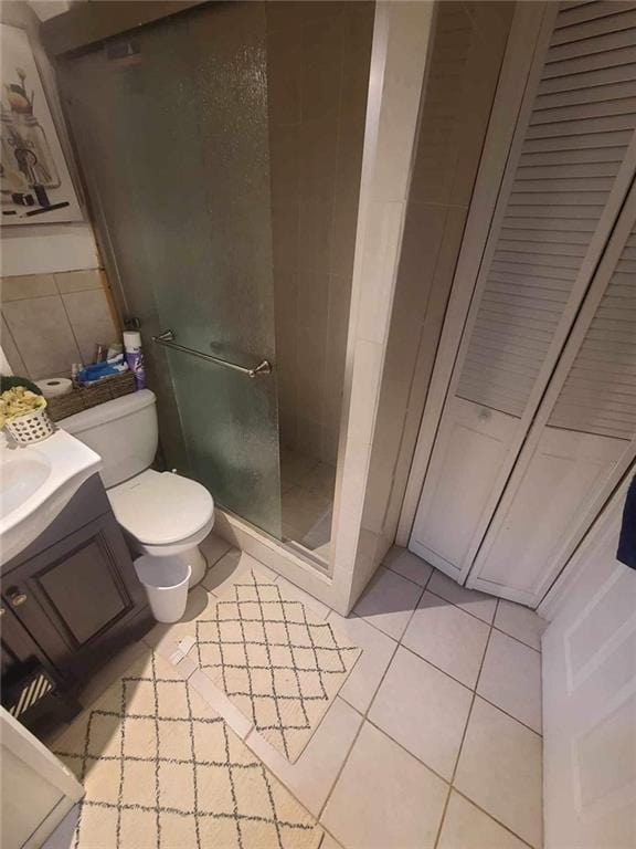 bathroom featuring tile patterned floors, vanity, toilet, and a shower with shower door