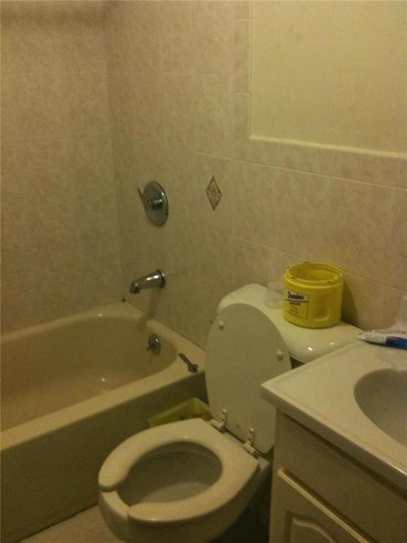 full bathroom with vanity, shower / bath combination, toilet, and tile walls