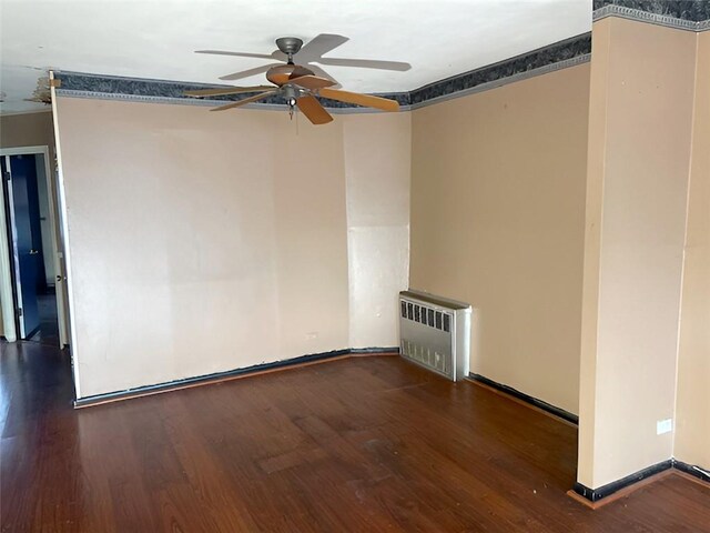 spare room featuring dark wood-type flooring, ceiling fan, and radiator heating unit