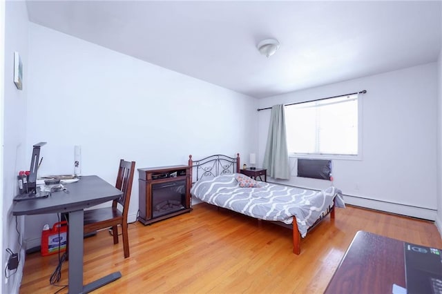 bedroom featuring wood-type flooring and a baseboard heating unit