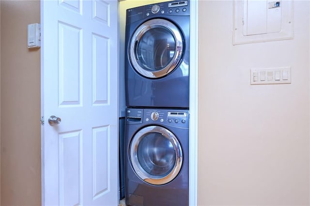 washroom featuring stacked washer and clothes dryer, electric panel, and laundry area