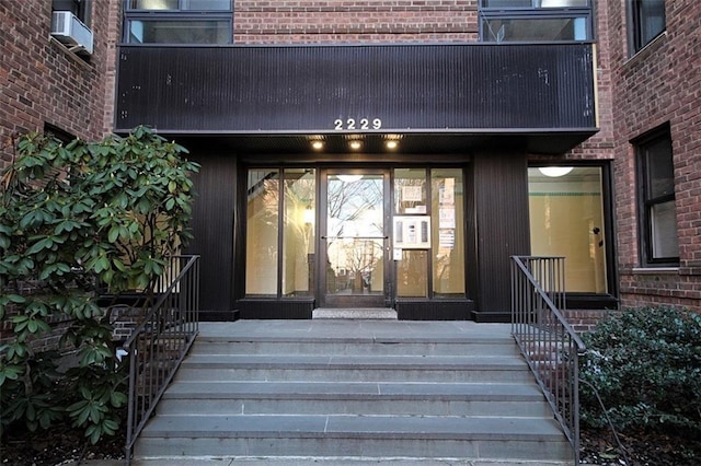 doorway to property featuring cooling unit and brick siding