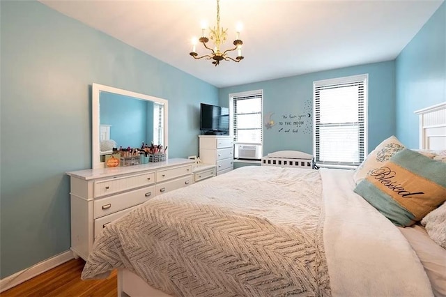 bedroom featuring an inviting chandelier, baseboards, and wood finished floors