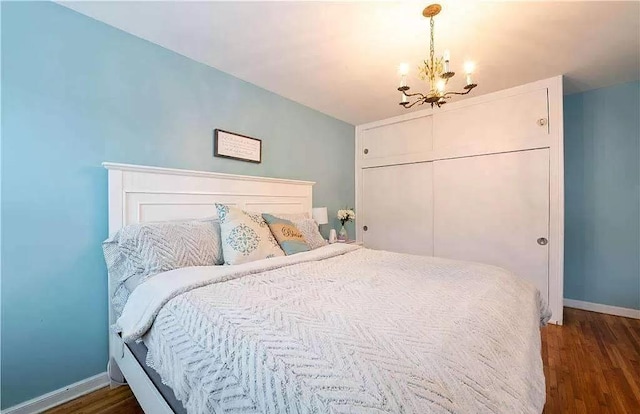 bedroom with an inviting chandelier, baseboards, a closet, and dark wood-type flooring