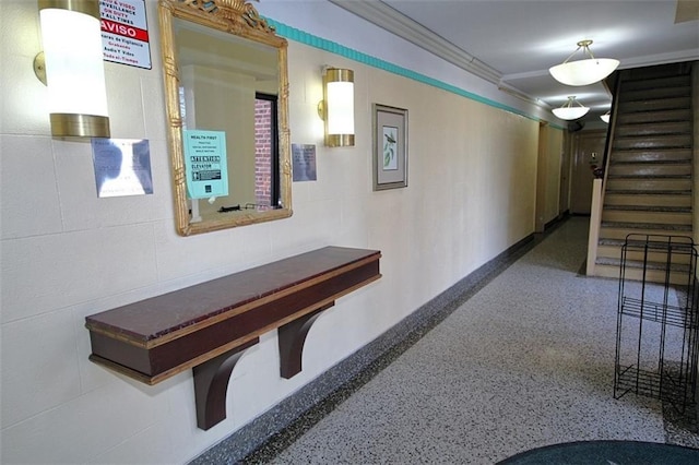 hallway featuring stairs, concrete block wall, speckled floor, and ornamental molding