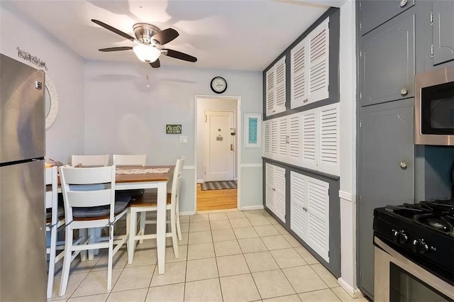 kitchen featuring ceiling fan, light tile patterned flooring, baseboards, and stainless steel appliances