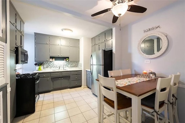 kitchen featuring light tile patterned floors, gray cabinets, stainless steel appliances, light countertops, and backsplash