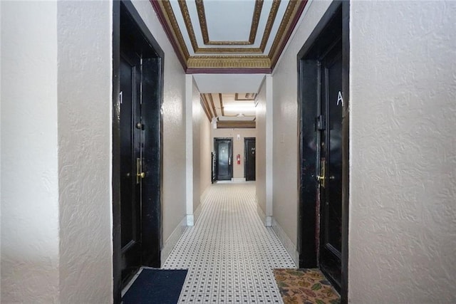 hallway featuring tile patterned floors, ornamental molding, baseboards, and a textured wall