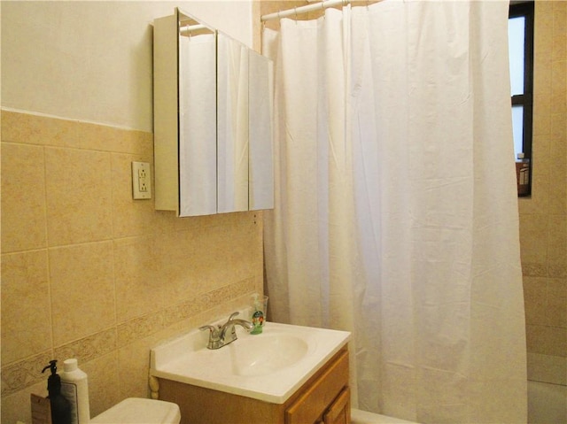 bathroom with tile walls, vanity, toilet, and walk in shower