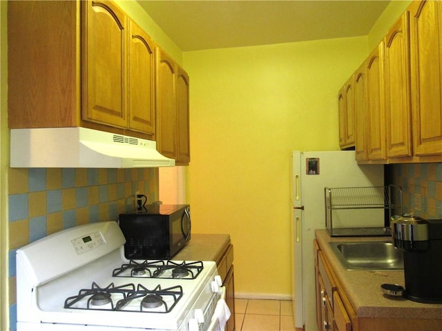 kitchen with white gas range, decorative backsplash, fridge, and light tile patterned flooring