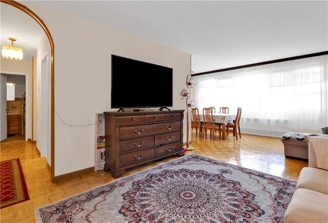 living room featuring an inviting chandelier, radiator heating unit, and light parquet flooring