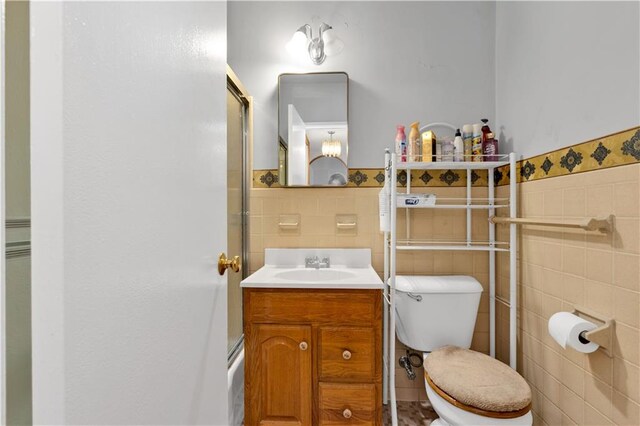 bathroom featuring vanity, toilet, tile walls, and walk in shower