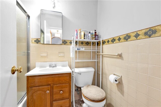 bathroom featuring vanity, tile walls, and toilet