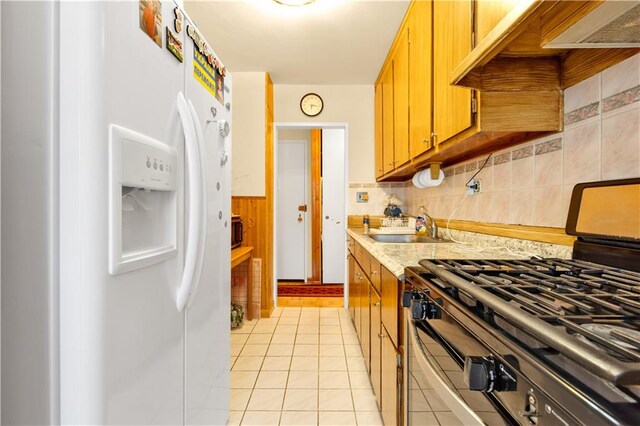 kitchen with backsplash, sink, white refrigerator with ice dispenser, light tile patterned floors, and gas stove