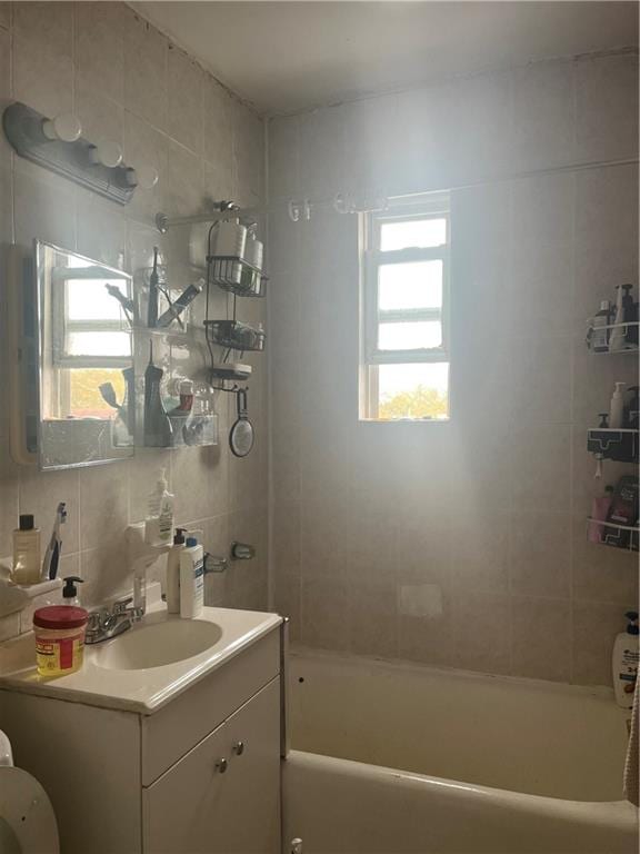 full bathroom featuring decorative backsplash, tile walls, vanity, and tub / shower combination