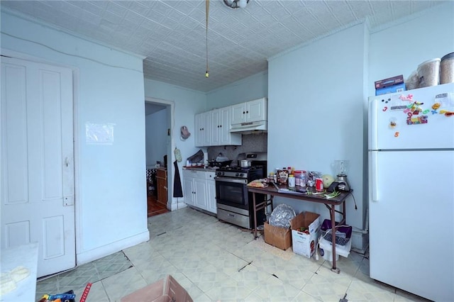 kitchen featuring gas range, white cabinetry, and white fridge