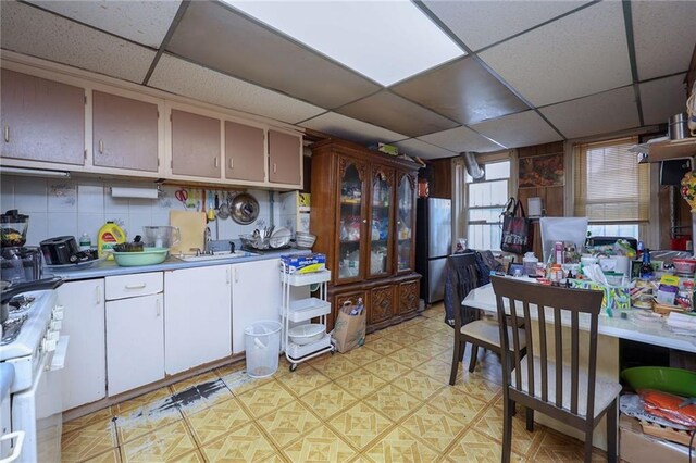 kitchen with stainless steel fridge, a paneled ceiling, white range with gas cooktop, and sink