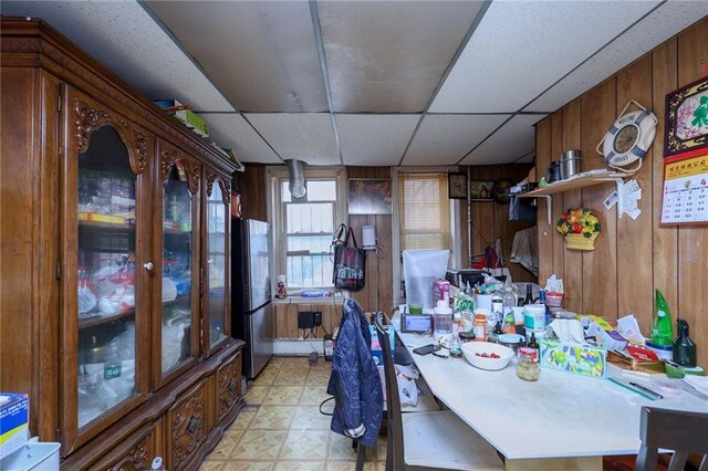 dining room with a drop ceiling and wood walls