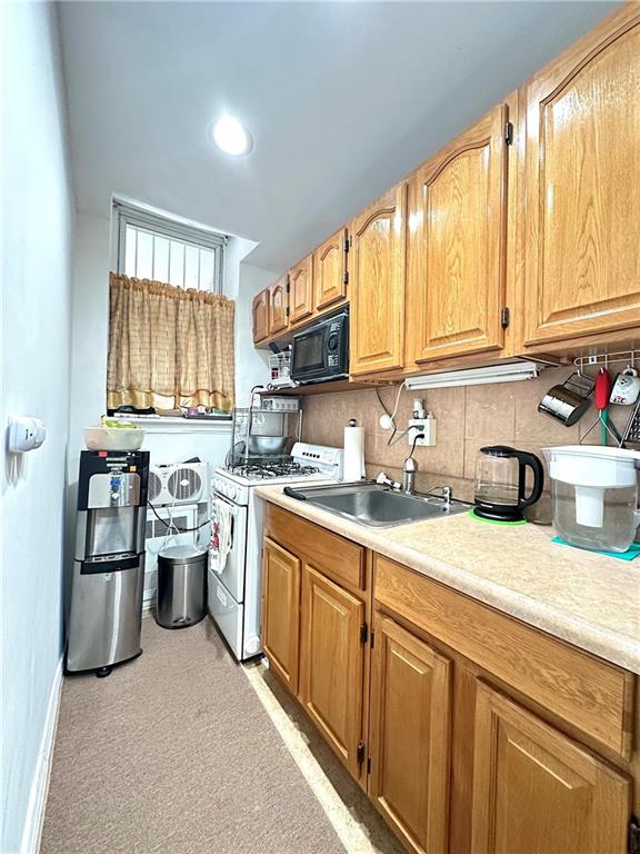 kitchen with tasteful backsplash, sink, and white gas range oven