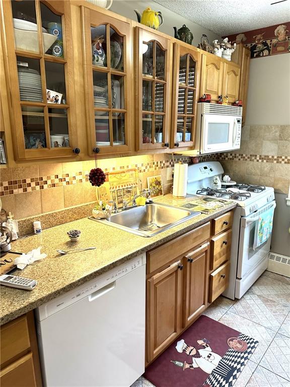 kitchen with white appliances, sink, a textured ceiling, and backsplash