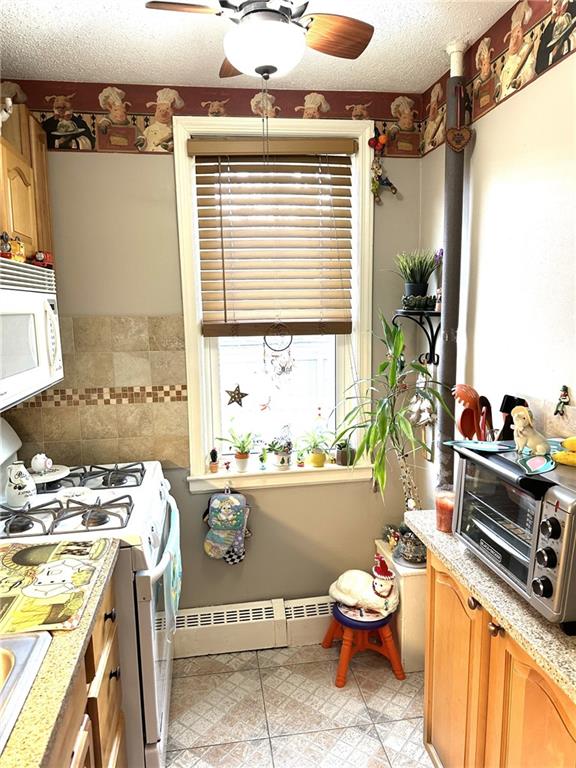 kitchen featuring ceiling fan, a textured ceiling, white appliances, and baseboard heating