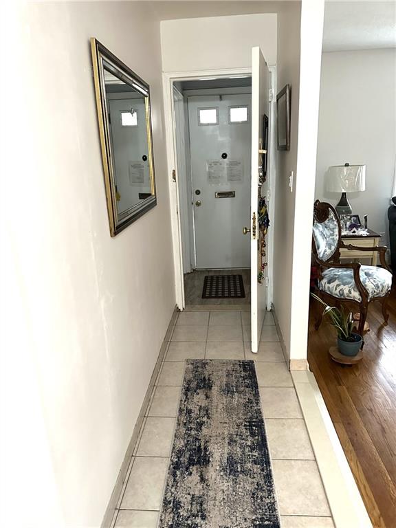 corridor with light tile patterned flooring and baseboards