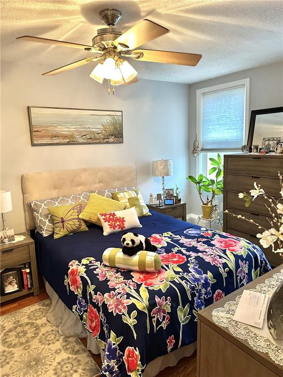 bedroom featuring a textured ceiling, light hardwood / wood-style flooring, and ceiling fan