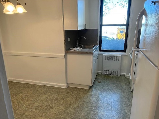 kitchen with dark tile floors, white fridge, sink, tasteful backsplash, and radiator heating unit