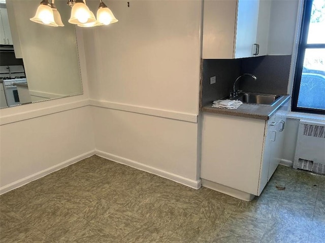 kitchen featuring a sink, white gas range oven, white cabinets, and radiator heating unit