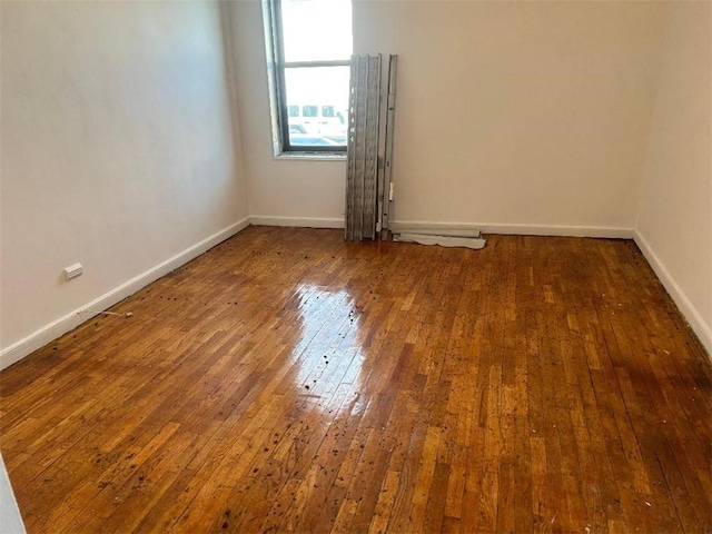 spare room featuring hardwood / wood-style floors and baseboards