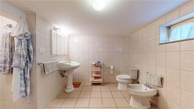 bathroom with tile patterned flooring, toilet, tile walls, and a bidet