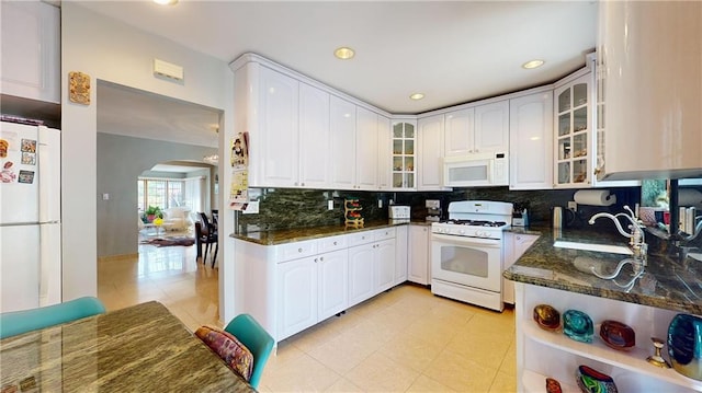 kitchen featuring white cabinetry, dark stone countertops, white appliances, and sink